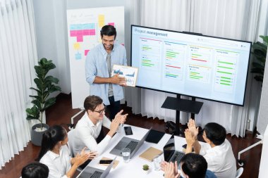 Proje yöneticisi monitörde proje yönetimi yazılım görüntülemesi, proje görevinin ilerlemesini izlemek ve toplantı masasında program planı yapmak suretiyle ekiple iletişim kurar ve işbirliği yapar. Tedbirli