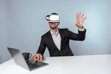 Bilgisayarla masada otururken ve VR gözlüğü takarken veri analizine bakan yetenekli bir iş adamı. Proje yöneticisi sanal gerçeklik sistemini kullanarak ya da metaevrende bağlantı kurarak çalışıyor. Sapma.