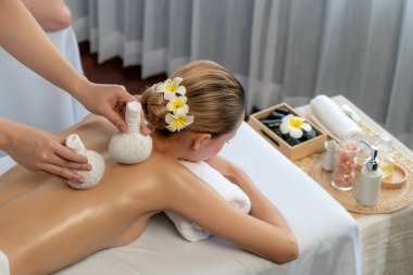 Sıcak bitkisel top spa masaj vücut tedavisi, masör kadın vücuduna nazikçe şifalı bitki torbası bastırıyor. Aromaterapi dinlenme sükuneti ve sükuneti kaplıca salonundaki atmosferi aydınlatıyor. Sessiz.
