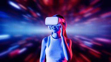 Zeki bir kadın, metaevreni birbirine bağlayan VR kulaklık takan neon ışıklarla çevrili duruyor. Gelecekteki siber uzay topluluğu teknolojisi. Uzaklara bakan zarif bir kadın ve tatmin edici bir şekilde gülümsüyor. Halüsinasyon.