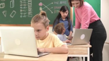 Beyaz çocuk çeşitli öğrenci kodlama mühendisliği komut ile çevrili kameraya bakarken programlama sistemine odaklanıyor. Happy öğretmen bilgisayar dersinde dizüstü bilgisayarda çalışan çocuklara destek oluyor. Pedagoji.