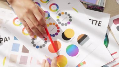 Üst görünüm yavaş çekim eli, grafik tasarımı için çalışan iki tasarımcının ya da tasarımcıdan yaratıcı kromatik konsültasyonda renk uygulaması arayan istemcinin masasının üzerinde. Değiştirilmiş