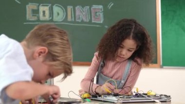 Dizüstü bilgisayar ekranında çalışan çeşitli öğrenci kodlama mühendisliği komut yazılımı ve yapay zeka programlaması yapıyor. Amerikalı kız, erkek makine tamir ederken ekipmanları teftiş ediyor. Pedagoji.