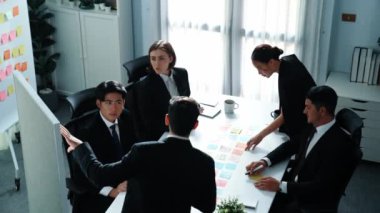 İş adamlarının üst görüşü pazarlama stratejisini açıklıyor ve renkli yapışkan notlar kullanarak fikri seçiyor. Profesyonel pazarlama ekibi toplantı odasında beyin fırtınası yapıyor ve finansal planlar yapıyor. Müdürlük.