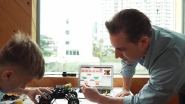 Öğretmen yardımı öğrencisi araba modelini tamir ediyor ve liseli çocuk STEM sınıfında robotu tamir etmek için ekipmanları dinlerken programlama sistemi ya da kodlama komutu veriyor. Arkadan bak. Öğretim