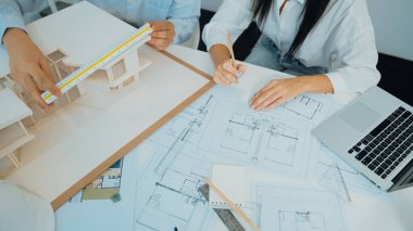 Profesyonel mühendis ev modelini tartartarken, yetenekli tasarımcı da planına yazar. Birlikte çalışmak, işbirliği, işbirliği. Yaratıcı tasarım ve takım çalışması konsepti. - Yakın çekim. Tertemiz.
