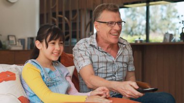 Grandfather and granddaughter together watch interesting entertainment media on TV. Old senior use technology communicate with young generation cross generation gap strengthen family bond. Divergence. clipart