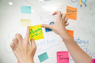 Profesyonel iş kadınının elini kapat ve iş planını sunarken renkli yapışkan notları beyaz tahtaya yapıştır. Yaratıcı iş toplantısı ve beyin fırtınası konsepti. Tertemiz..