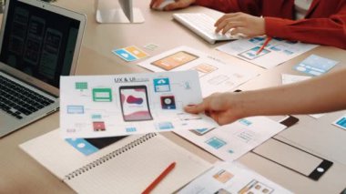 Mobil uygulama için kullanıcı arayüzü prototipini ofis çalışanlarına sunan harika bir şirket çalışanı. UX UI tasarımcısı kağıt üzerinde simge tasarımının işlevini açıklıyor. Sinerjik