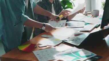 Takım ayakta dikilirken ve yorum yaparken müdürün fikir yazma konusunda üst düzey görüşü. Profesyonel tasarımcı logosu renk paletine bakarken ve renkli kalemle fikri kağıda yazarken. Sempozyum.