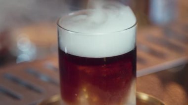 Viski kokteyli sunumunda dumanlı dumanlı dumanlı içki servisi yapan kırpılmış el barmeni içecek tezgahında özel, lezzetli, yaratıcı bir reklam içeceği öneriyor. Vinosity.