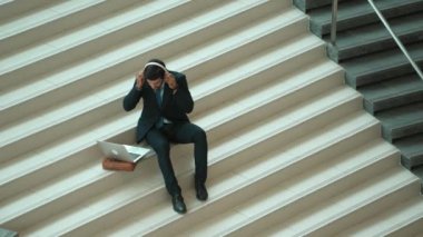 Merdivenlerde otururken kulaklıktan müzik dinleyen zeki bir iş adamı. Mutlu menajer dans ederken ya da müzikle uğraşırken gülümsüyor. Yatırımcı iyi haberler alıyor, terfi alıyor. Sevinçli..