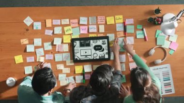 Toplantı masasında renk paletleriyle birlikte yapışkan notlar kullanarak yaratıcı tasarımcının beyin fırtınası fikrinin üst görüntüsü. Akıllı takımın hava görüntüsü tabletten simge grafiği seçiyor. Sempozyum.