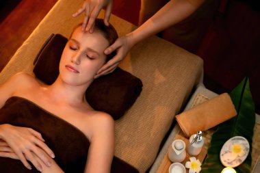 Beyaz kadın stres önleyici kafa masajı yapmaktan ve lüks otel veya otelde sıcak mum ışığında yüz güzelliği eğlencesi yapmaktan zevk alıyor. Sessiz.