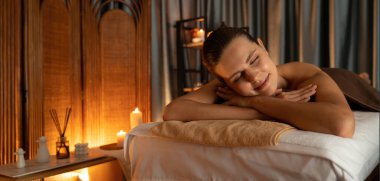 Beyaz kadın müşteri stres önleyici spa masajının keyfini çıkarıyor ve lüks otel ya da otelde sıcak mum ışığında güzellik teniyle eğleniyor. Sessiz.