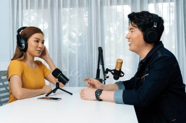 Gülümseyen radyo etkili sunucusu kulaklık takıyor kadın konuşmacı ile röportaj yapıyor sosyal medya internet sitesinden dinleyicilere bilgi paylaşıyor stüdyo kaydında sabah canlı yayın kanalı. İnfobahn.