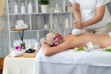 Sıcak bitkisel top spa masaj vücut tedavisi, masör kadın vücuduna nazikçe şifalı bitki torbası bastırıyor. Aromaterapi dinlenme sükuneti ve sükuneti kaplıca salonundaki atmosferi aydınlatıyor. Sessiz.
