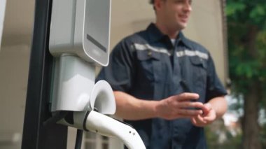 Teknisyen ev EV şarj istasyonu kurar, müşteri akıllı telefonunda şarj durumunu izlemek ve şarj takvimlerini evde ayarlamak için EV uygulamasına hizmet desteği sağlar. Titiz