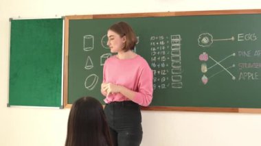 Profesyonel mutlu öğretmen sınıfta otururken sevimli bir öğrenciden not defteri topluyor. Kafkas hocası sınıfta dolaşırken çocukların ödevlerini topluyor. Eğitim konsepti. Pedagoji.