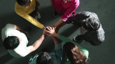 Zeki iş adamlarının birlikte çalışıp el ele tutuşması. Bir grup yetenekli iş adamının beyin fırtınası yapıp toplantı odasında el ele tutuşmalarının havadan görüntüsü. Sempozyum.