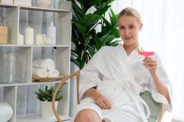 Güzellik ya da vücut bakımı güzellik salonu yaşam tarzı konsepti. Bornoz giyen bir kadın lüks otel kaplıcalarında ya da tatil odasında içkiyle rahatlıyor. Tatil ve boş zaman rahatlığı. Sessiz.