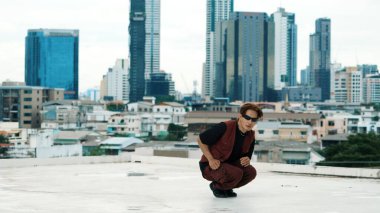 Profesyonel Asyalı break dansçı B çocuk dansı yaparken çatıda çok kültürlü arkadaşlar var. Genç modern dans grubu hip hop hareketi yapıyor. Tarz, moda, aksiyon. Açık hava sporu 2024. Hiphop.