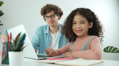 American student looking at camera while working on laptop with dad sitting and looking at laptop screen to check engineering code. Happy school girl smiling while study about generate ai. Pedagogy. clipart