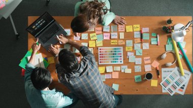 Toplantı masasında renk paletleriyle birlikte yapışkan notlar kullanarak yaratıcı tasarımcının beyin fırtınası fikrinin üst görüntüsü. Akıllı takımın hava görüntüsü tabletten simge grafiği seçiyor. Sempozyum.