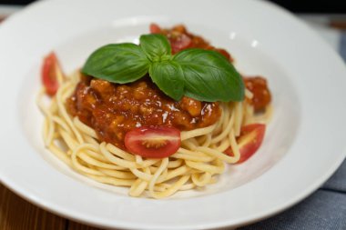 Özel ev yapımı çiğ spagetti, domates sosu ve makro fotoğraf odağı fesleğeni karışımı beyaz tabağa servis edilen unsurlar. Varsayım.