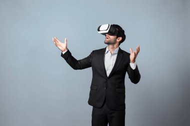 İş adamı VR gözlüğü kullanarak veri analizi yapıyor. Proje yöneticisi beyaz arka planda takım giyerken metaverse ya da sanal gerçeklik dünyasına girerek iş stratejisini kontrol ediyor. Sapma.