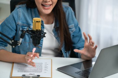 Sosyal medyada kulaklıkla canlı yayın yapan Asyalı sunucu modern stüdyoda yaşam koçluğu veya pazarlama dinleyicilerini selamlıyor. Taktik.