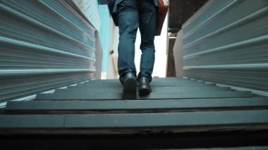 Merdivenlerden çıkan başarılı iş adamının bacağına yakın plan. Müdürün iş yerini değiştirmesi, yeni bir şey keşfetmesi, gelişmesi, terfi etmesi ya da gün ışığına çıkması. Yükseliyor. Bacağa odaklan. Sevinçli..