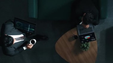 Meslektaşı dizüstü bilgisayarını tutarken ve performansını desteklerken, profesyonel proje yöneticisinin çalışma alanına yürüyüp tablet üzerinde çalışmasının yukarıdan aşağıya hava görüntüsü. İş ekibi birlikte çalışıyor. Müdürlük.