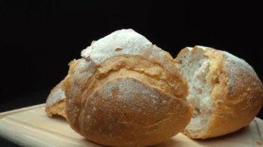 Koyu arkaplanda yırtık taze ekmek parçalarını yakın plan çek. Tahta tepsiye konmuş Fres ekmeklerinin makro fotoğrafları. Yakınlaştır ve kamera hareketini döndür. Gurme ve fırın konsepti. Pabulum.
