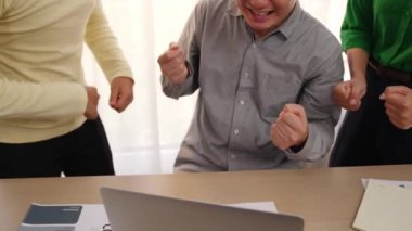 Yavaş çekim heyecanlı ve mutlu yaratıcı iş adamları grubu toplantı masasında başarılarını kutluyor. Etrafta dokümanlar ve dizüstü bilgisayarlar var. Yaratıcı iş başarısı kavramı. Değiştirilmiş