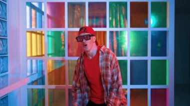 Serbest stil tişört giyerken sokak müziği çalan mutlu hipster. Gece kulübünde neon ışıkla dururken çekici break dansçı dans ve hareketli hareketler yapıyor. Mutluluk.