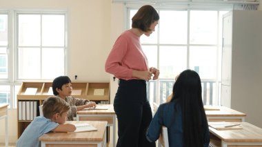Sınıfta çeşitli çocuklar sınıf ödevlerini yaparken, Kafkasyalı öğretmen sınıfta yürüyor ve öğrenci ödevlerini kontrol ediyor. Çeşitli zeki öğrenciler ilkokulda ders veriyor ve not alıyor. Pedagoji.