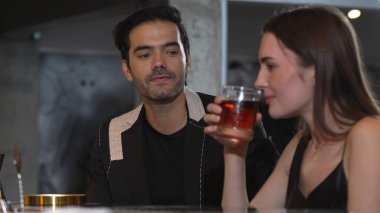 Barmen, dumanlı klasik viskiyi kokteyl ile karıştırıyor. Bir bayana içki tadıyor ve kulüpteki grup misafirlerine içecek tezgahında lezzetli bir içki ikram ediyor. Vinosity.