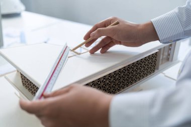 Modern ofiste cetvel ve mimari ekipmanlar kullanarak ev modelini ölçen profesyonel mimar elin yakın çekimi. Yaratıcı iş tasarımı konsepti. Eline odaklan. Tertemiz..