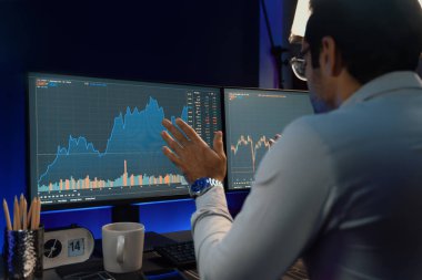 Akıllı tüccar işadamı, karanlık oda gecesinde neon ışıklı ofisteki arama pazarında yüksek kârla ekranda bilgisayar ve bilgisayar üzerinde dinamik borsa yatırımları üzerinde yoğunlaşıyor. Tahmin et..