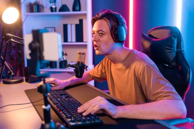 Oyun kanalı, online oyun oynayan akıllı flamalı oyun sunucusu, kulaklık takan, neon ışıklandırma odasındaki takım oyuncusuyla akıllı telefondan canlı yayında konuşan izleyiciler. Bireysel.