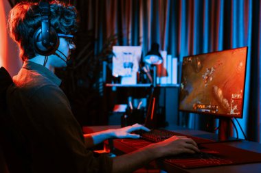Savaş arenasında çoklu oyunlar takımıyla Moba 'da savaşan genç oyun flamasının sunucu kanalı, neon dijital ışık modern odasındaki arka görüntü ile bilgisayar monitöründe kulaklık takıyor. Toplayıcı.