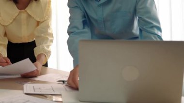 Mimarlık ve güvenlik mühendisi, modern ofiste dizüstü bilgisayarda mimari belge ve ahşap blokla sergilenen planlar hakkında tartıştı. - Yakın çekim. Tanımlama.