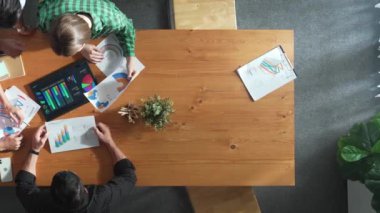 Akıllı iş adamlarının yukarıdan görünüşü toplantıda verileri analiz eder. Birlikte çalışan bir grup iş adamı ve toplantı masasına yerleştirilen tabletin mali tablosuna bakıyorlar. Cemaat.