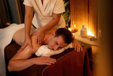 Beyaz erkek müşteri stres önleyici spa masajının keyfini çıkarıyor ve lüks otel ya da oteldeki ortam kaplıcalarında sıcak mum ışığında güzellik teniyle eğleniyor. Sessiz.