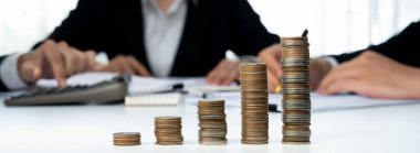 Büyüyen madeni para yığını iş yatırımını ve ekonomik büyümeyi simgeliyor. Finansal hedefe ulaşmak ve maksimum kâr sağlamak için finansal planlama yapan iş adamları. Kurnaz.