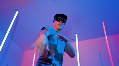 Beyaz dansçının gösterişli gözlükler taktığı ve break dans yaptığı alçak açılı kamera. Çekici adam kendinden emin bir şekilde kameraya bakarken enerjik bir performans ve hareket gösterdi. Mutluluk.