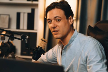 Sunucu kanalı akıllı yayıncı laptopta canlı sosyal medya uygulaması arıyor, kulaklık takıyor ve modern ofis stüdyosundaki mikrofonu kullanıyor. Bireysel.