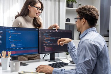 Masada çalışan erkek programcının karşısında duran kadın meslektaşım iki bilgisayar ekranında kodlama web sitesi yazılım sistemi projesini tartışmak için tam yığın veri dizaynı ile karşılaştırıyor. Varsayım.