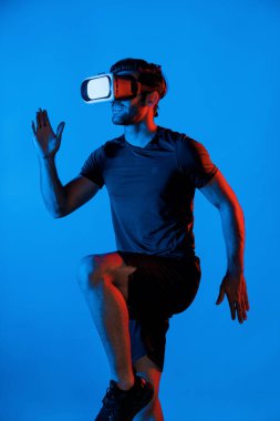 Beyaz tenli zeki bir adam neon ışıklı VR gözlük takarken koşuyor. Sanal gerçeklik kulaklığı kullanırken günlük kıyafetleri olan ya da egzersiz yapan mutlu bir insan. Yenilik teknolojisi konsepti. Sapma.